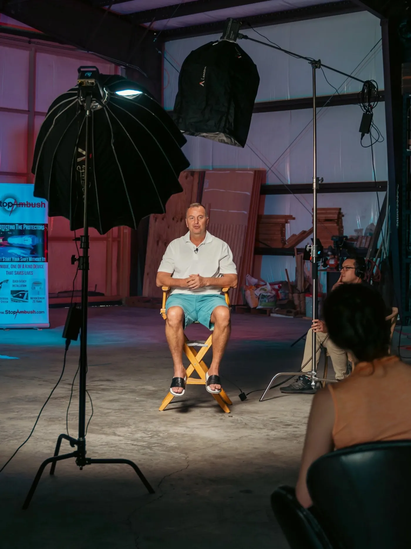 An interview set in a warehouse with two softboxes lighting a man in a director's chair